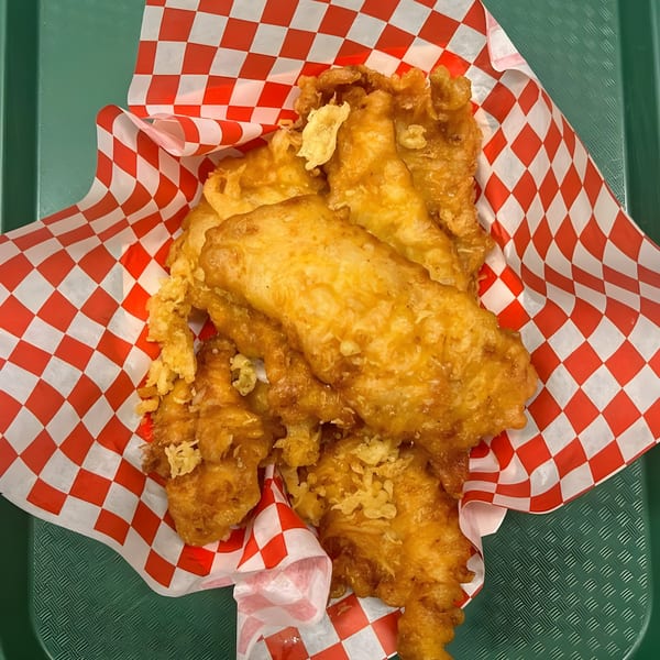 Golden-brown battered fish pieces from Alfie's Fish & Chips, served in red and white checkered paper.