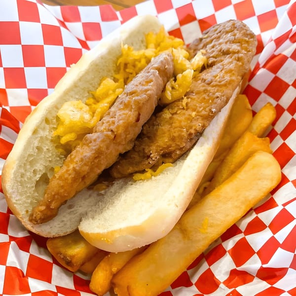 Alfie's Fish & Chips' fish sandwich with fries, served in a red and white checkered paper.