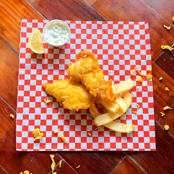 Alfie's Fish & Chips: two pieces of golden-brown fried fish with thick-cut chips, lemon, and tartar sauce.